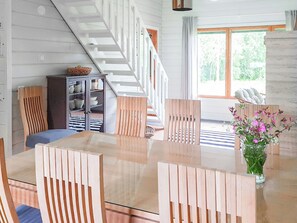 Ein großzügiger Wohnbereich mit einem Holzessttisch, Stühlen, einer Couch und einer Treppe.