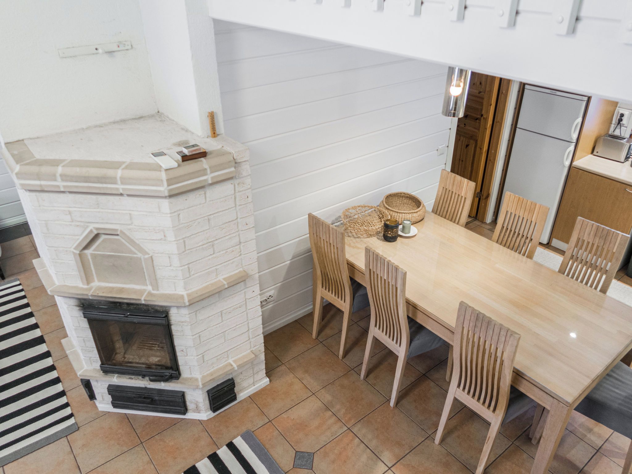 A kitchen with a built-in fireplace, wooden dining table, and chairs.
