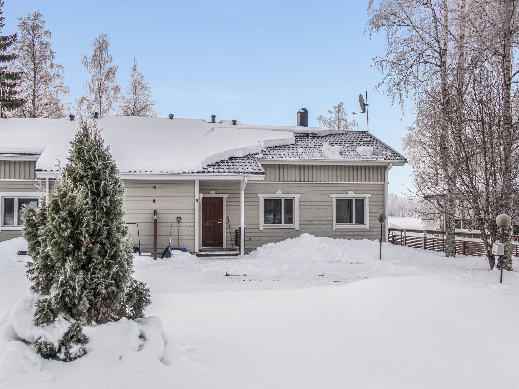 Ein zweistöckiges Haus mit verschneitem Dach und einem kleinen Vorgarten.
