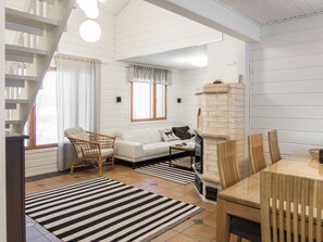 A modern living room with a sofa, a dining table, and a fireplace. - Vacation home Ruska by Interhome (Sotkamo)