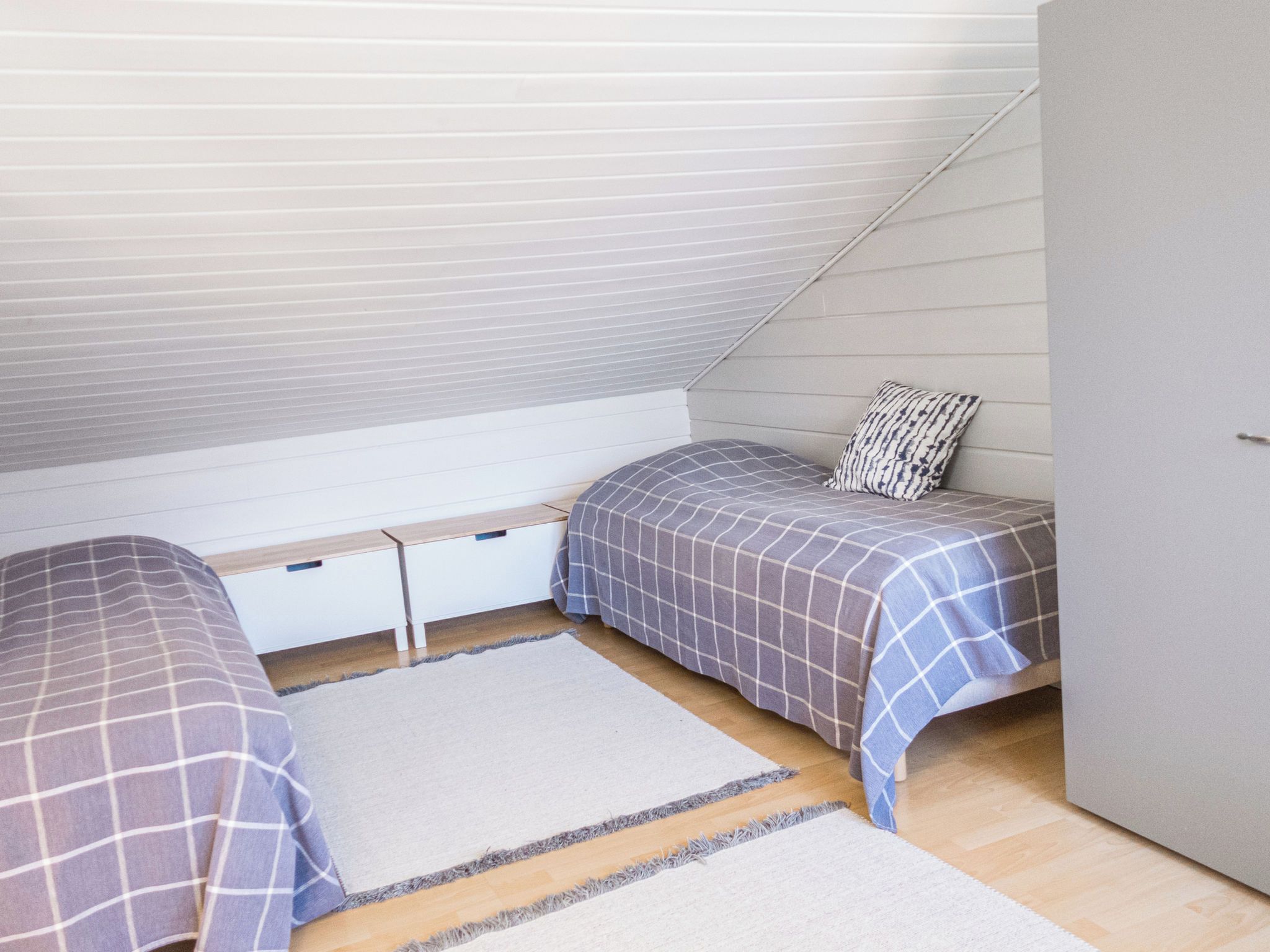Ein kleines, gemütliches Zimmer mit zwei Betten, einer Bank und einer Tür.