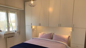 Une chambre à coucher avec un lit, une armoire blanche et une fenêtre avec des stores.