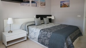 A bedroom with a bed, bedside table, lamp, and wall art. - Apartamento Premium un Dormitorio con Terraza (Fuengirola)