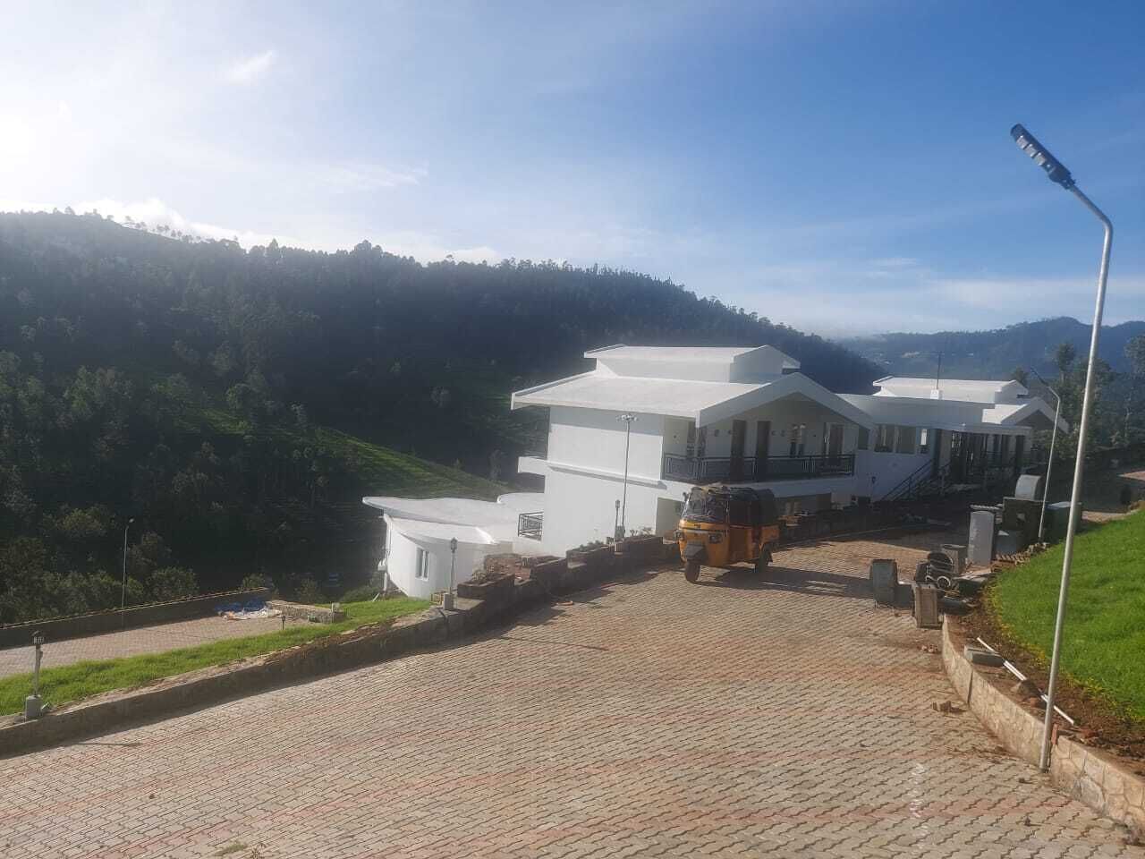 Um edifício moderno com um caminho de paralelepípedos e um auto-rickshaw estacionado.