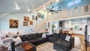 A spacious living room with a sectional sofa, a wooden coffee table, and a staircase leading to an upper level. - The Ascent - Waterfront Home w Priv Dock & Pool (Point Venture)