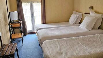 A hotel room with two beds, a desk, a chair, and a window with curtains.