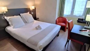 Une chambre d’hôtel avec un lit, deux tables de chevet, un bureau, une chaise et une fenêtre.