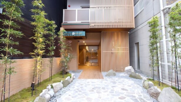 A modern building with a stone pathway leading to a wooden door. - HOTEL FURIN (Fukuoka)