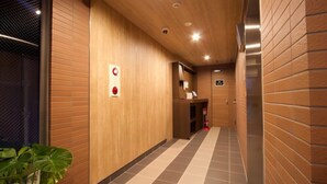 A hallway with wooden panel walls, a tiled floor, and a fire extinguisher on the right. - HOTEL FURIN (Fukuoka)