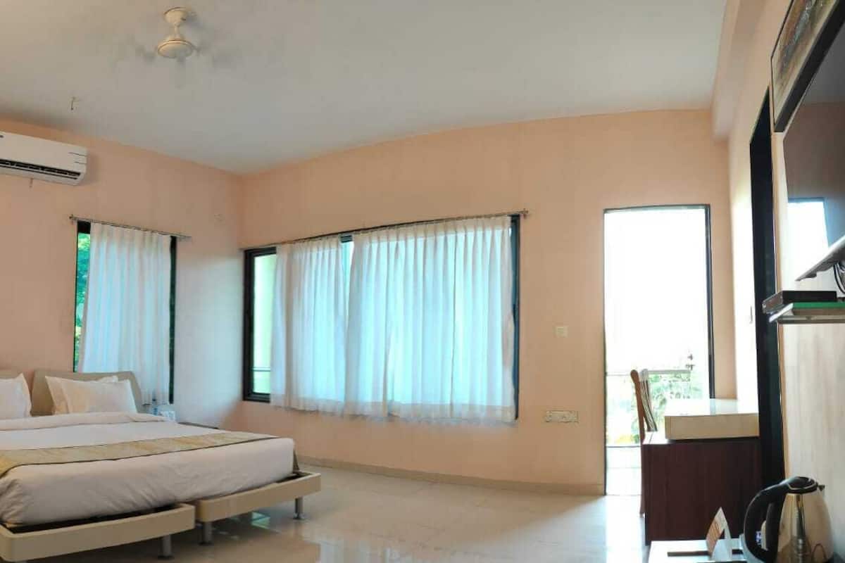 A bedroom with a bed, an air conditioning unit, and large windows with curtains.