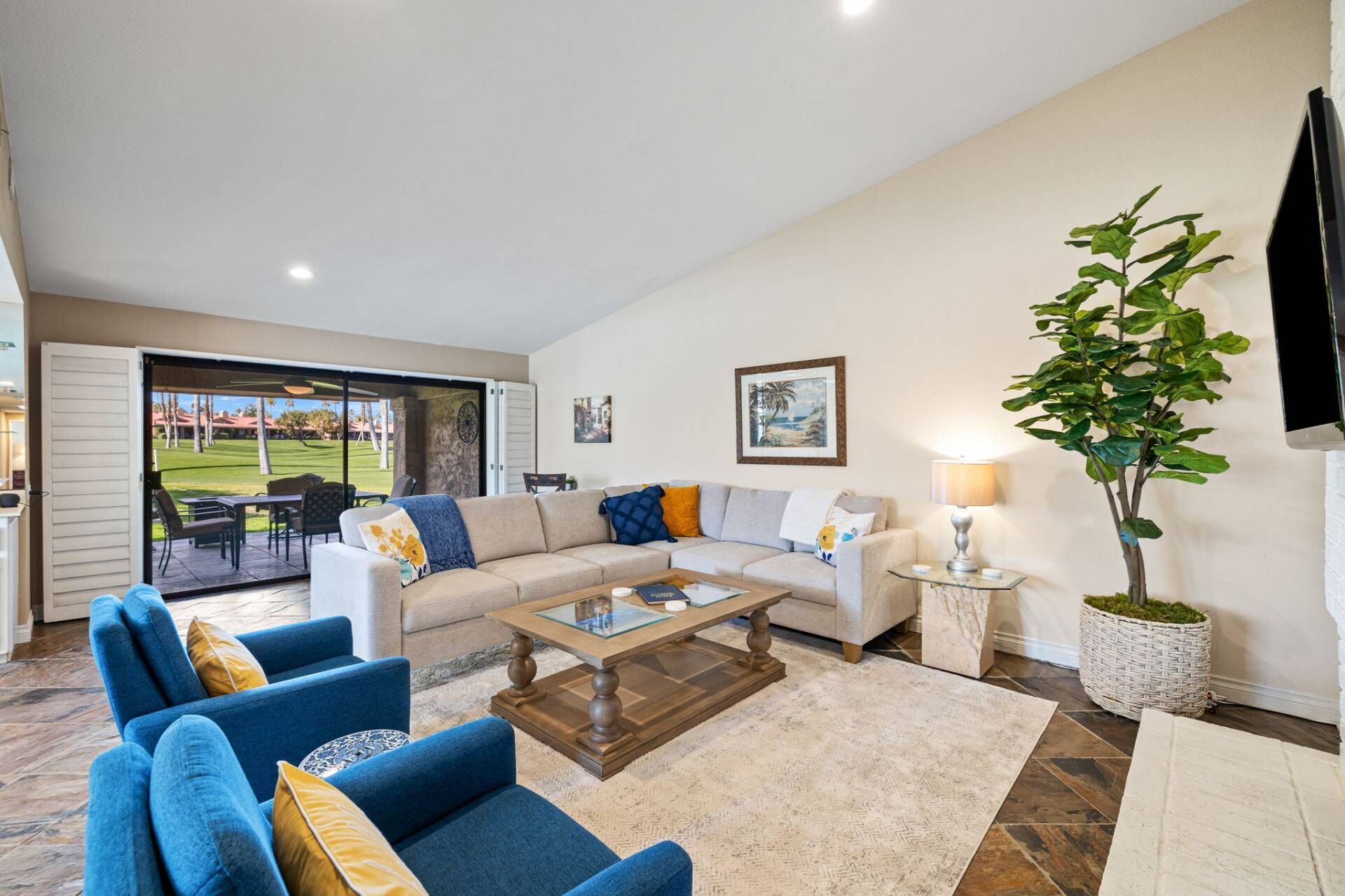 A living room with a sofa, armchairs, a coffee table, and a potted plant.