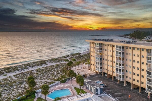 Un hôtel avec piscine, vue sur la plage et coucher de soleil.