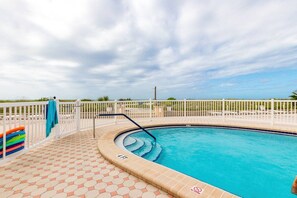 A swimming pool with a tiled deck, a white fence, and a clear sky. - Gulf, Beach, Pool View Balcony on Venice Beach (Venice)
