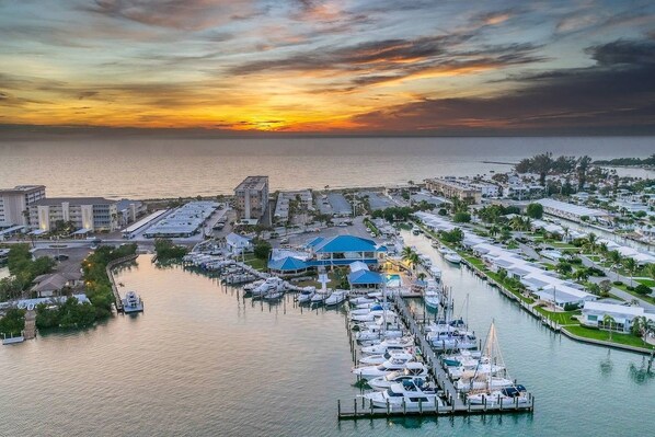 A marina with boats docked, a blue-roofed building, and a sunset over the water. - Gulf, Beach, Pool View Balcony on Venice Beach (Venice)