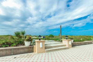 A paved walkway leading to a beach with steps, potted plants, and two street lamps. - Gulf, Beach, Pool View Balcony on Venice Beach (Venice)