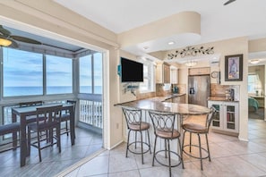 A kitchen with a large island, bar stools, and a view of the ocean.