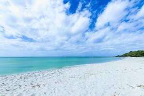 A beach with white sand and clear turquoise water under a partly cloudy sky. - Gulf, Beach, Pool View Balcony on Venice Beach (Venice)