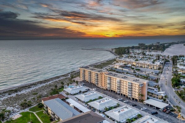 A coastal hotel with multiple buildings, a beach, and a sunset.