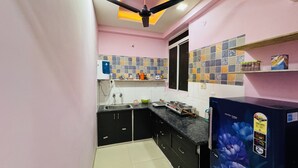 A kitchen with a black countertop, a water dispenser, a window, and a ceiling fan.