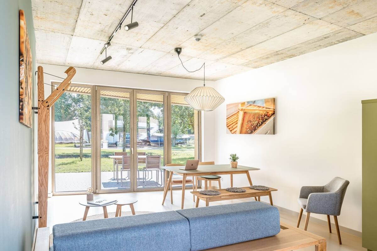 Una sala de estar moderna con un ventanal grande, un sofá, una mesa de comedor y una silla.