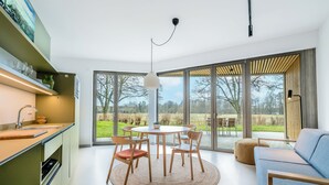 A modern kitchen with a dining area, large windows, and a view of the outdoors. - 360° Apartmenthotel - by teamgeist (Heidesee)