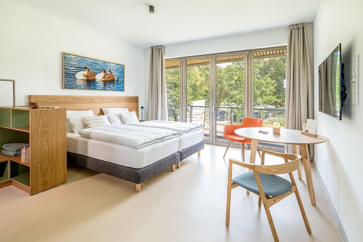 Habitación de hotel moderna con una cama grande, un escritorio y vistas al exterior.