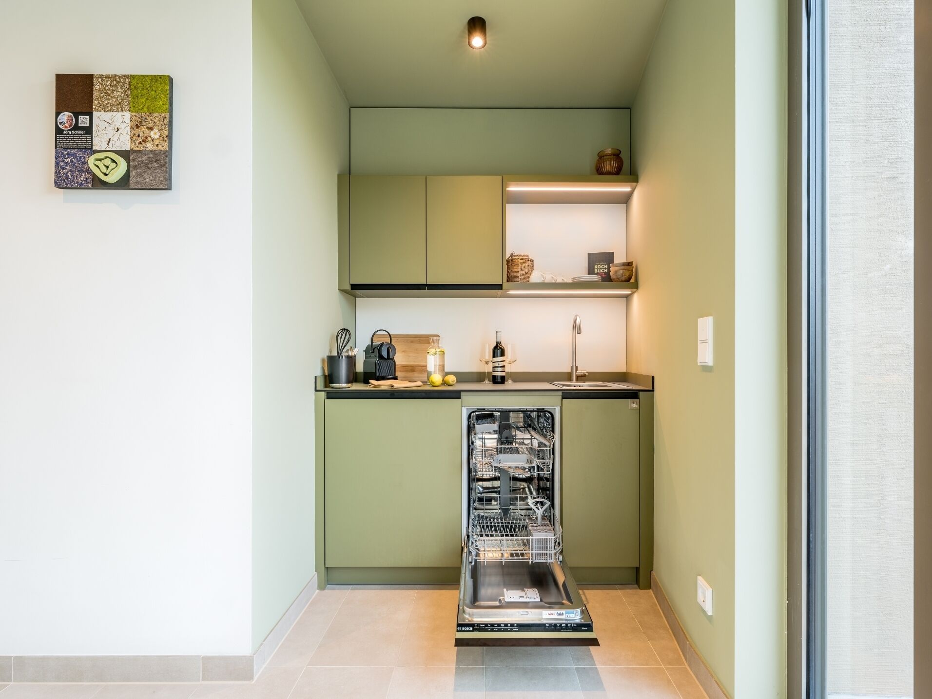 A compact kitchen with a dishwasher, a sink, and a small countertop with various items.