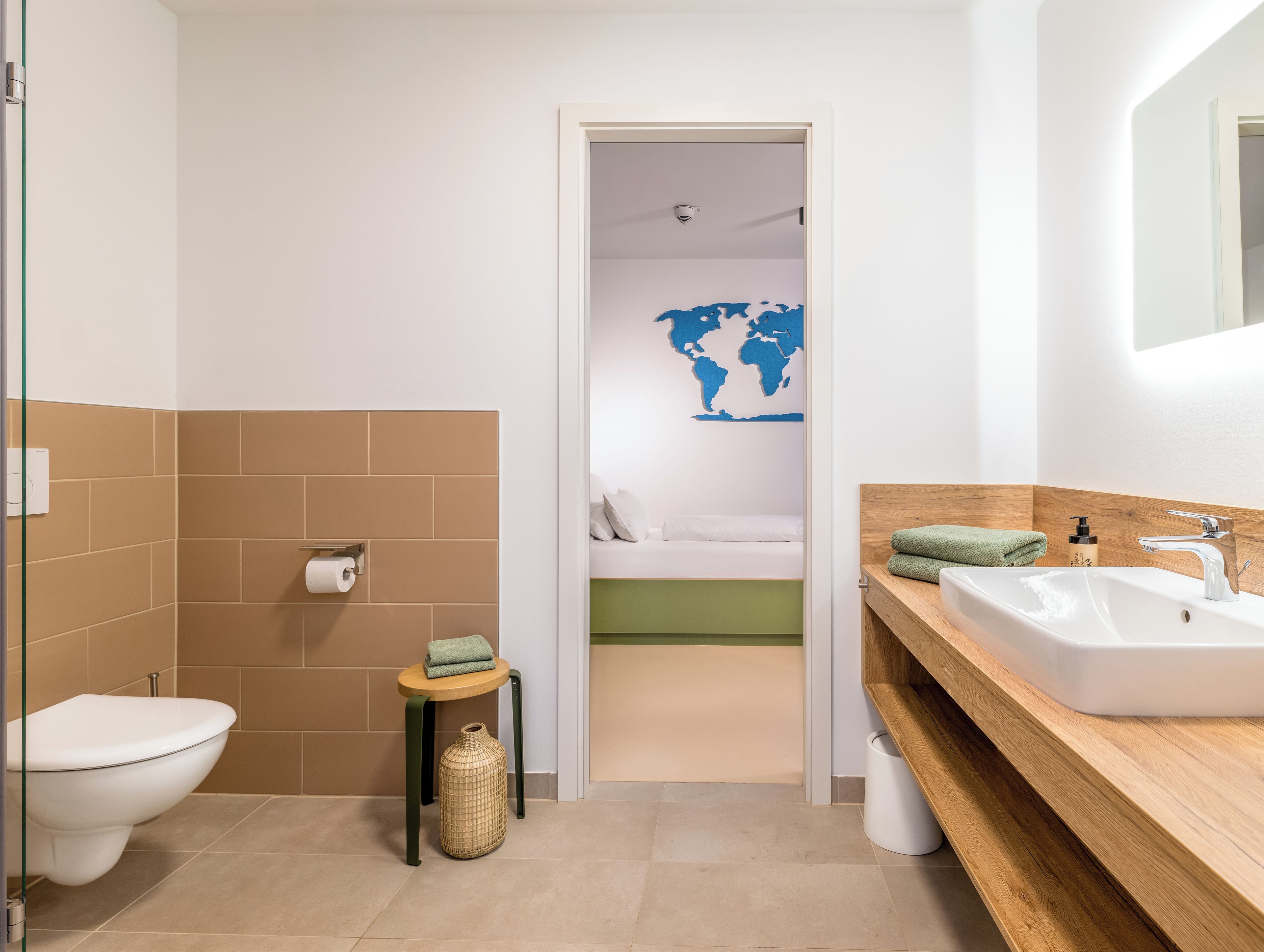 A modern bathroom with a toilet, bidet, sink, and a small table with a towel.