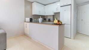 Una cocina moderna con armarios blancos, encimera de madera y microondas integrado.