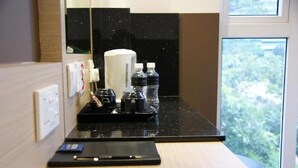 A hotel room with a black countertop, a coffee maker, water bottles, and a small tray. - The Snooze Hotel Bugis (Singapore)