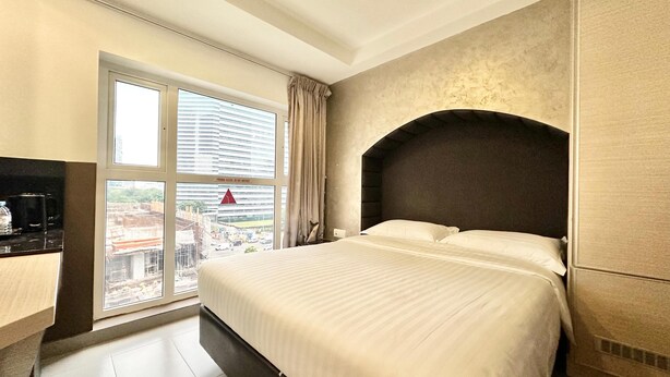 A hotel room with a large bed, a desk with a coffee maker, a TV, and a window with a city view. - The Snooze Hotel Bugis (Singapore)