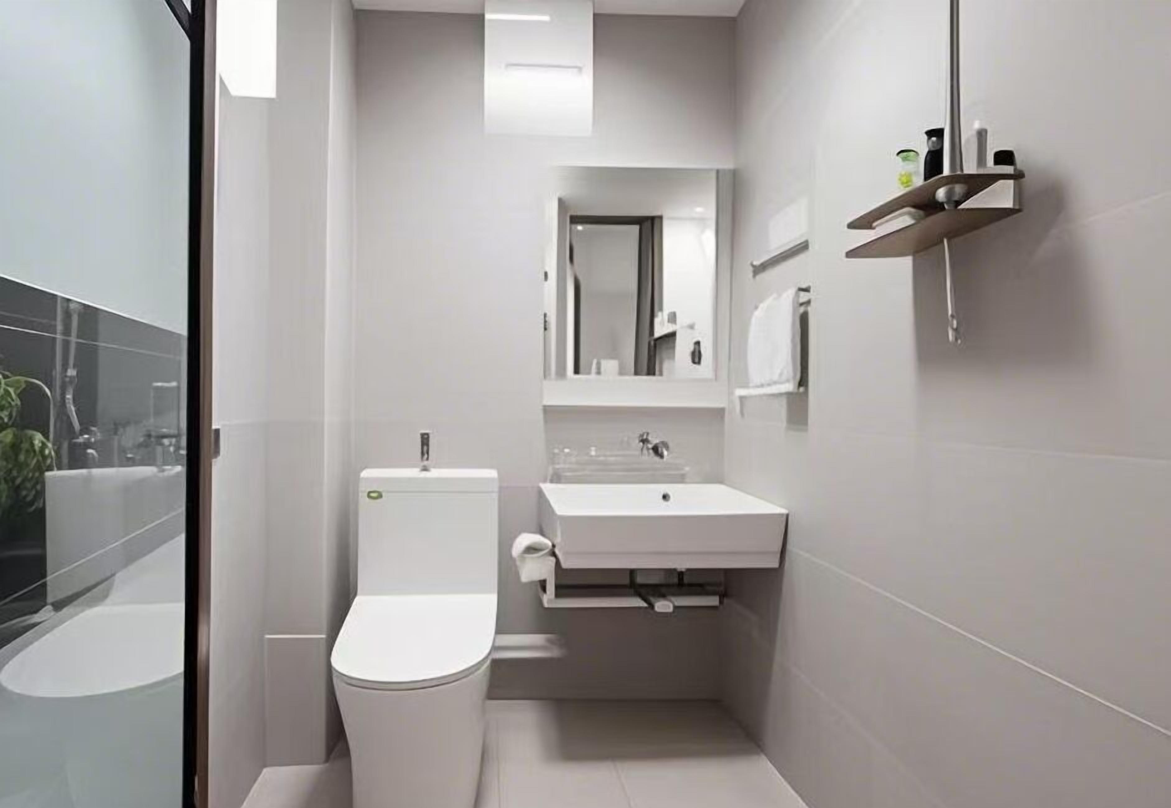 A modern bathroom with a toilet, sink, and mirror.