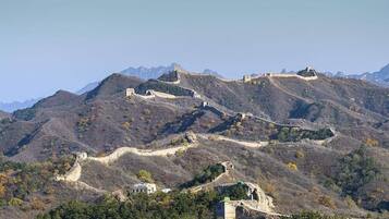 Paisaje montañoso con una muralla histórica y torres de vigilancia.