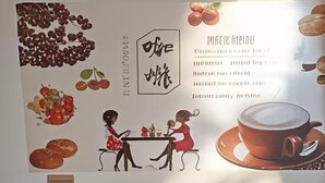 Un coin café équipé d’une machine à café, de tasses et d’une affiche accrochée au mur.