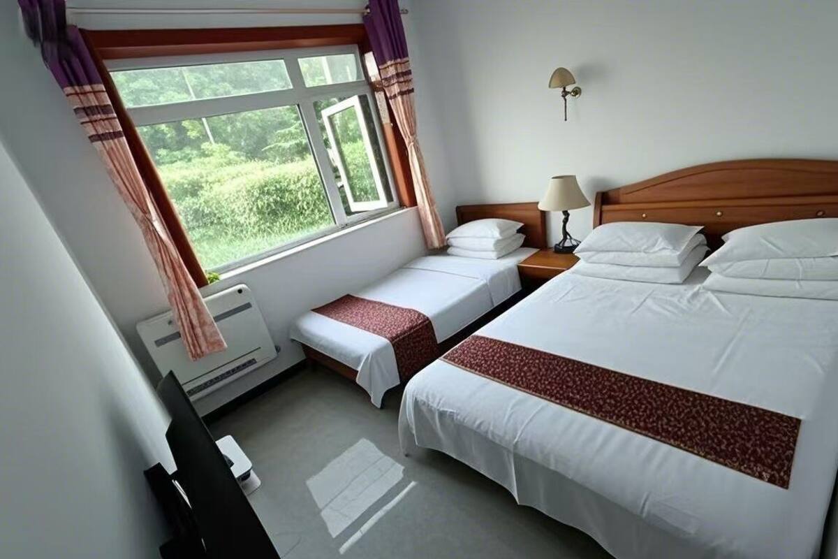 Habitació d'hotel amb dos llits, una taula de treball i una finestra amb cortines.