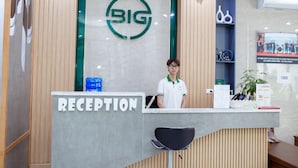 Een receptiebalie met een 'BIG' logo, een bord met de tekst 'RECEPTION' en een medewerker die erachter staat.