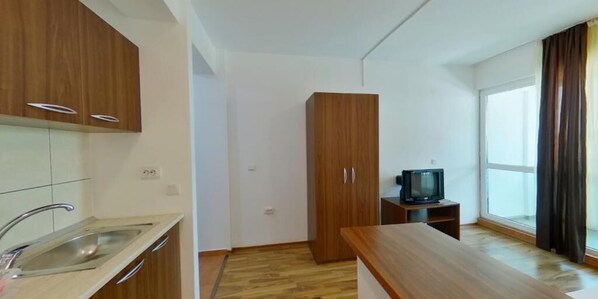 Una cocina moderna con armarios de madera, un lavamanos empotrado y un televisor de pantalla plana sobre una mesita.