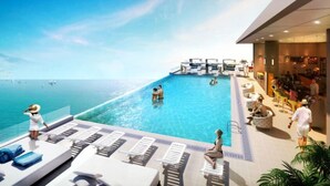 A poolside area with lounge chairs, a bar, and a view of the sea.