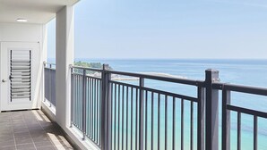 A balcony with a view of the sea, a door, and tiled flooring.