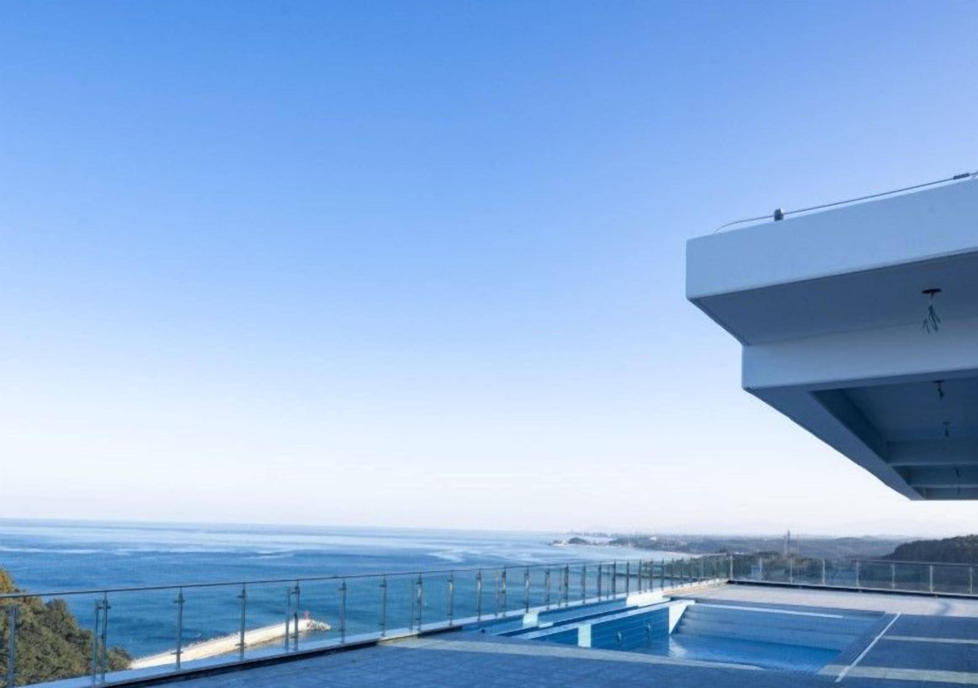 A modern building with a pool overlooking the ocean.