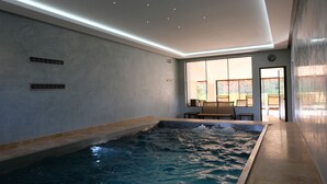 A modern indoor swimming pool with a view of the outdoors through large windows. - Chateau de Maillat (Maillat)