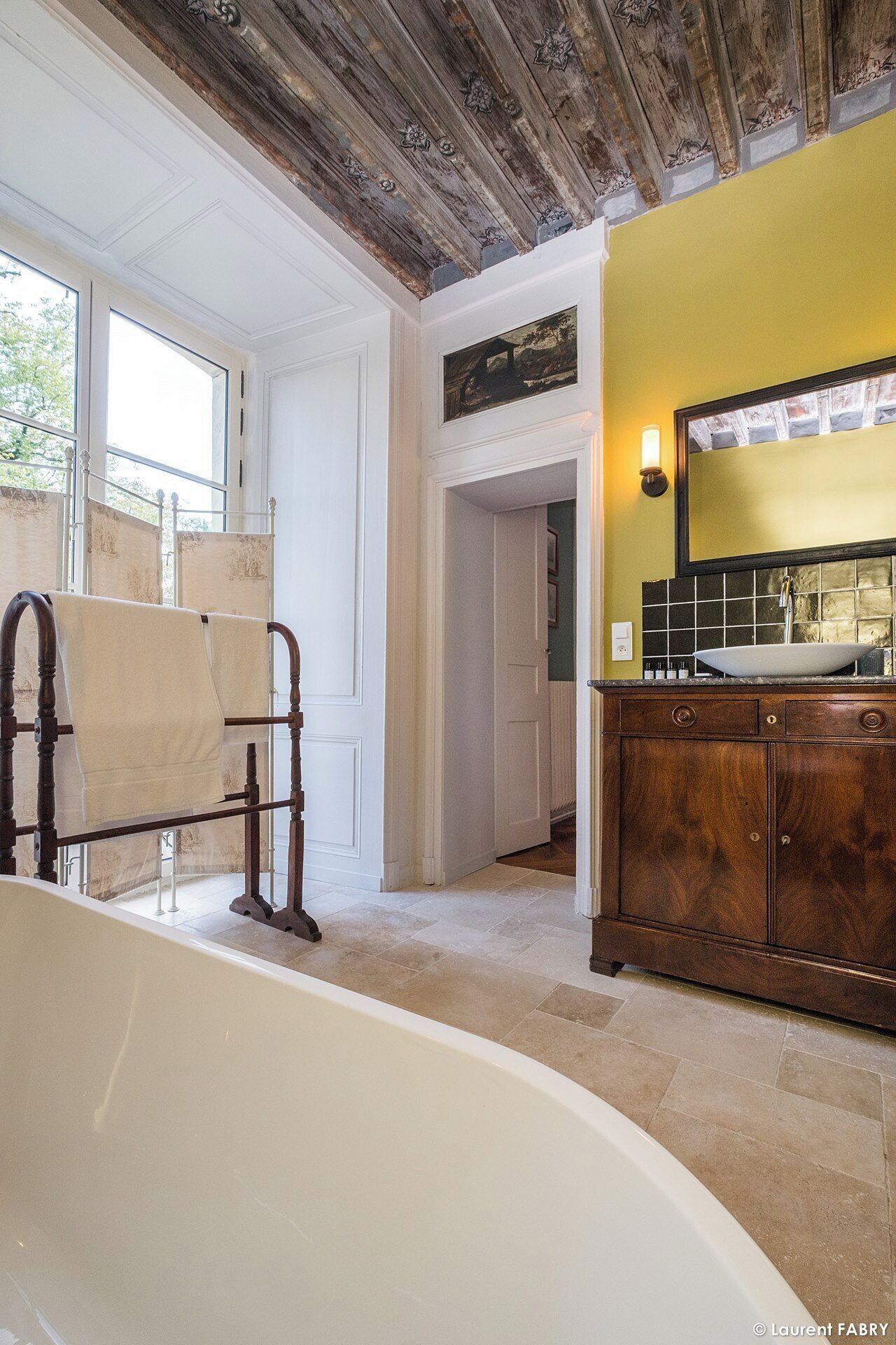 A bathroom with a bathtub, wooden vanity, and a large mirror.