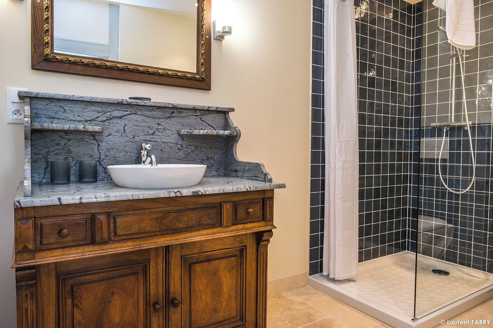 A bathroom with a marble vanity, a large mirror, and a glass-enclosed shower area.