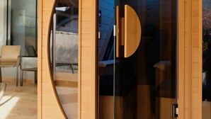 A modern room with a wooden cabinet, a glass door, and a chair. - Chateau de Maillat (Maillat)