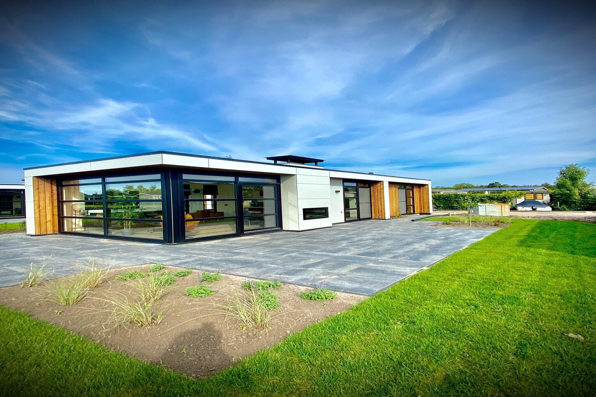A modern house with large glass windows, a flat roof, and a paved driveway.