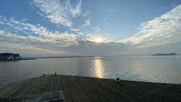 Un molo di legno che si estende sull'acqua calma, con un tramonto sullo sfondo.