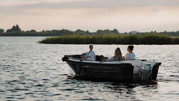 Un petit bateau à moteur avec trois personnes à bord, naviguant sur une étendue d’eau dont la côte est visible au loin.