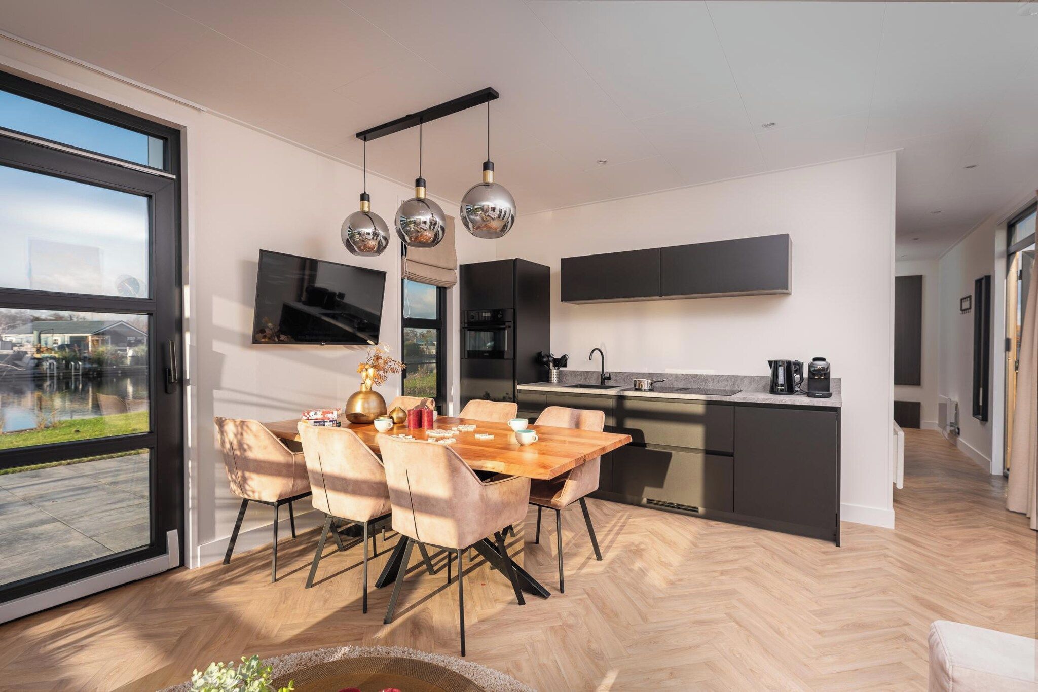 Een moderne keuken met een eethoek, grote ramen en uitzicht op de omgeving.