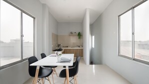 A modern apartment with a dining area, kitchen, and large windows. - Cove Veranda (Jakarta)