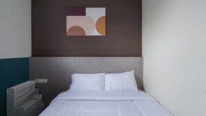 A hotel room with a bed, a nightstand, and a wall-mounted abstract art piece. - Cove Veranda (Jakarta)